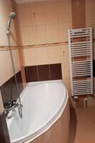 Un baño con una bañera, un cabezal de ducha y un perchero para toallas.