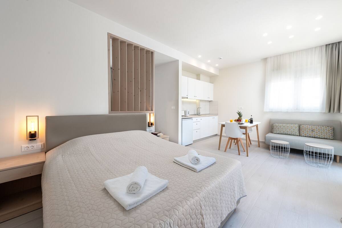A modern hotel room with a large bed, a desk, and a sofa.