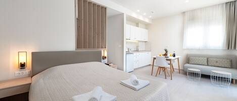 Quarto de hotel moderno com uma cama grande, uma mesa de trabalho e um sofá.