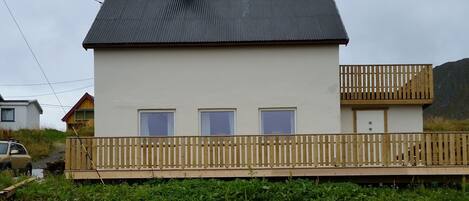 A two-story building with a balcony, a flat roof, and a wooden fence.