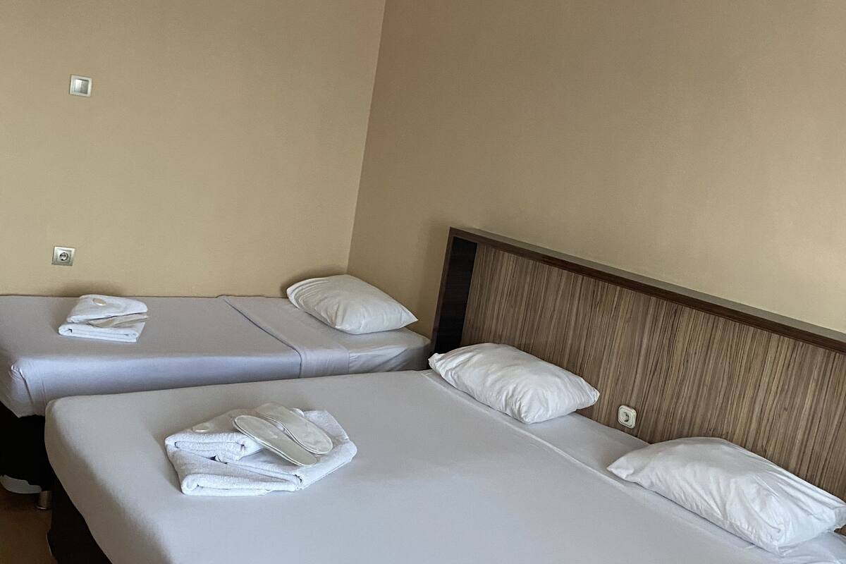 A hotel room with two beds, each with white linens and pillows, and a wooden headboard.