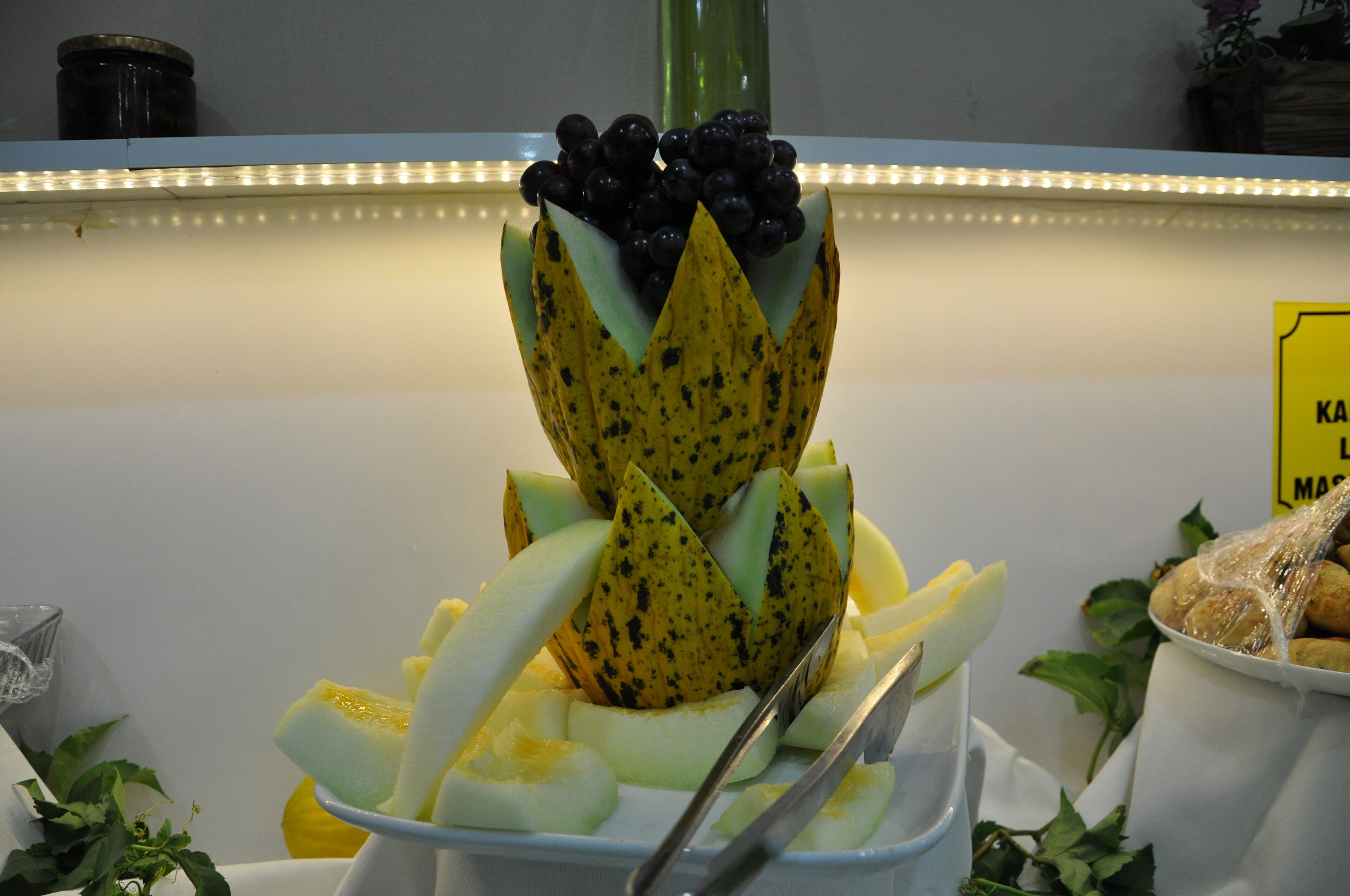 Een presentatie van fruit met een banaan, meloen en bosbessen.