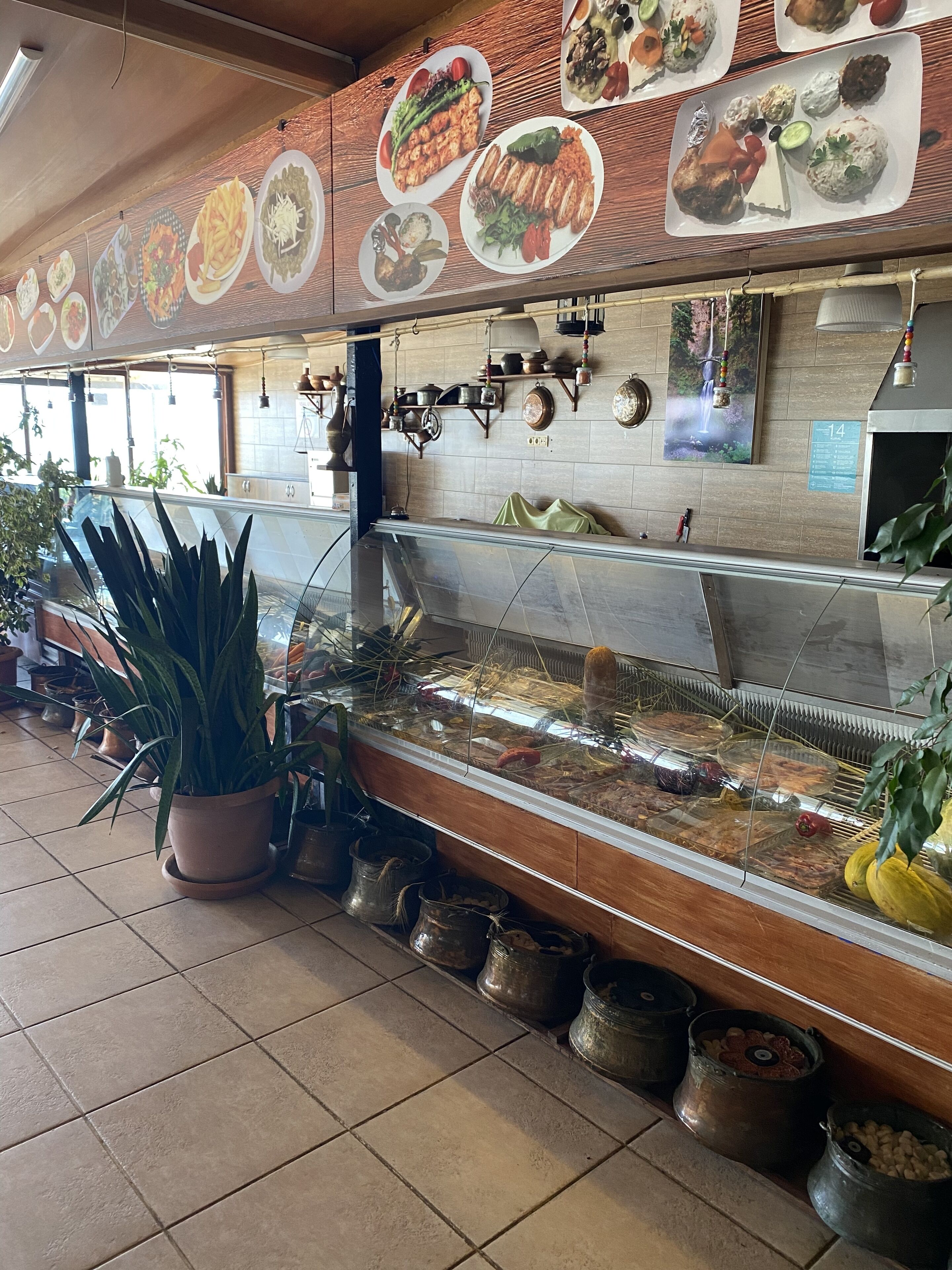 Zona de bufé con diversos platos exhibidos en la pared y una vitrina con alimentos.