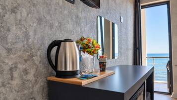 A modern kitchen with a kettle, a vase with flowers, and a view of the sea.