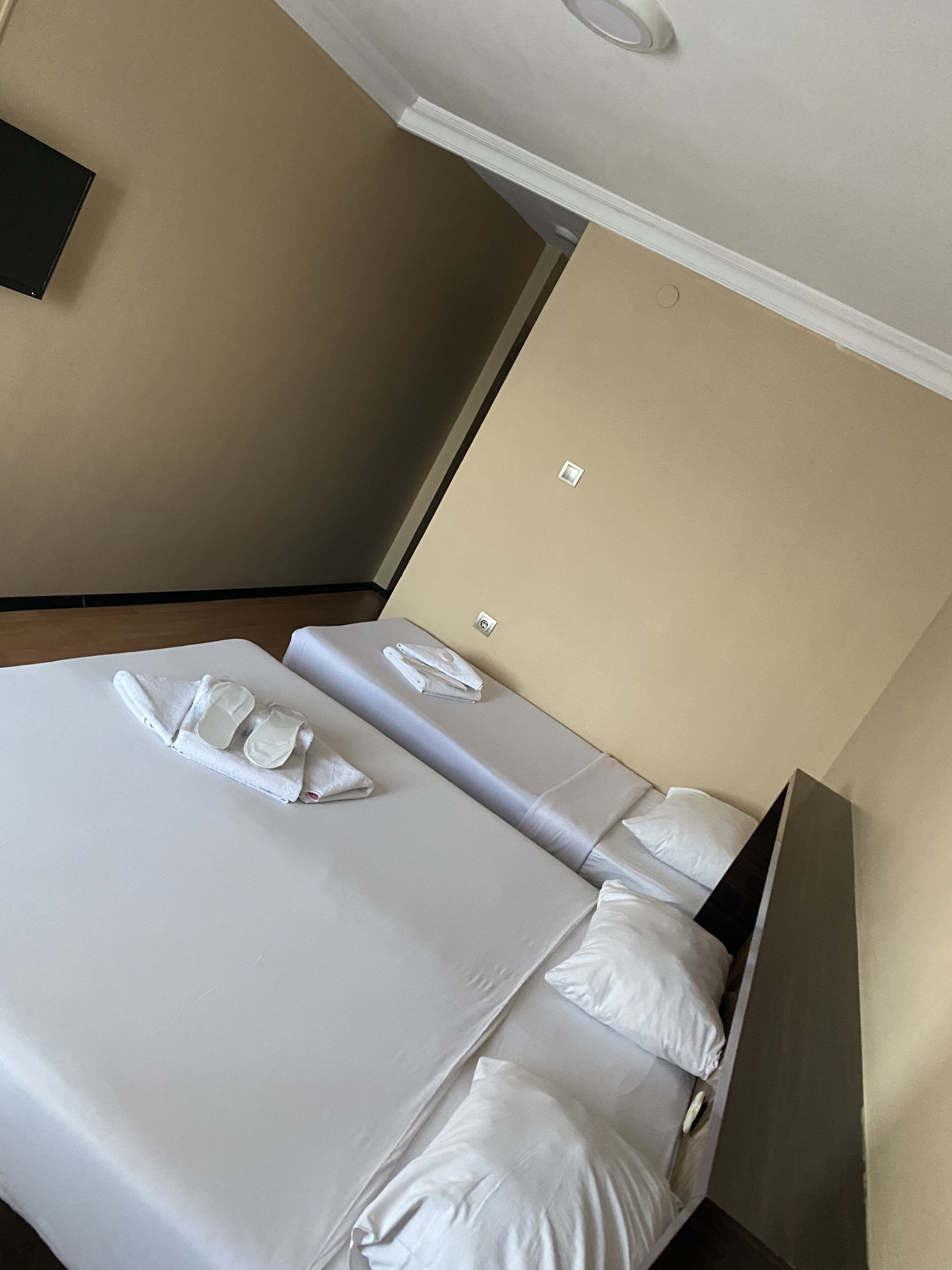 A hotel room with a neatly made bed, a small table, and a wall-mounted TV.