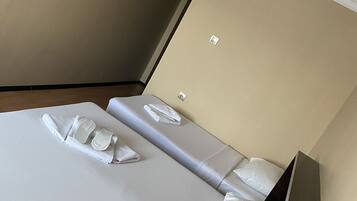 A hotel room with a neatly made bed, a small table, and a wall-mounted TV.