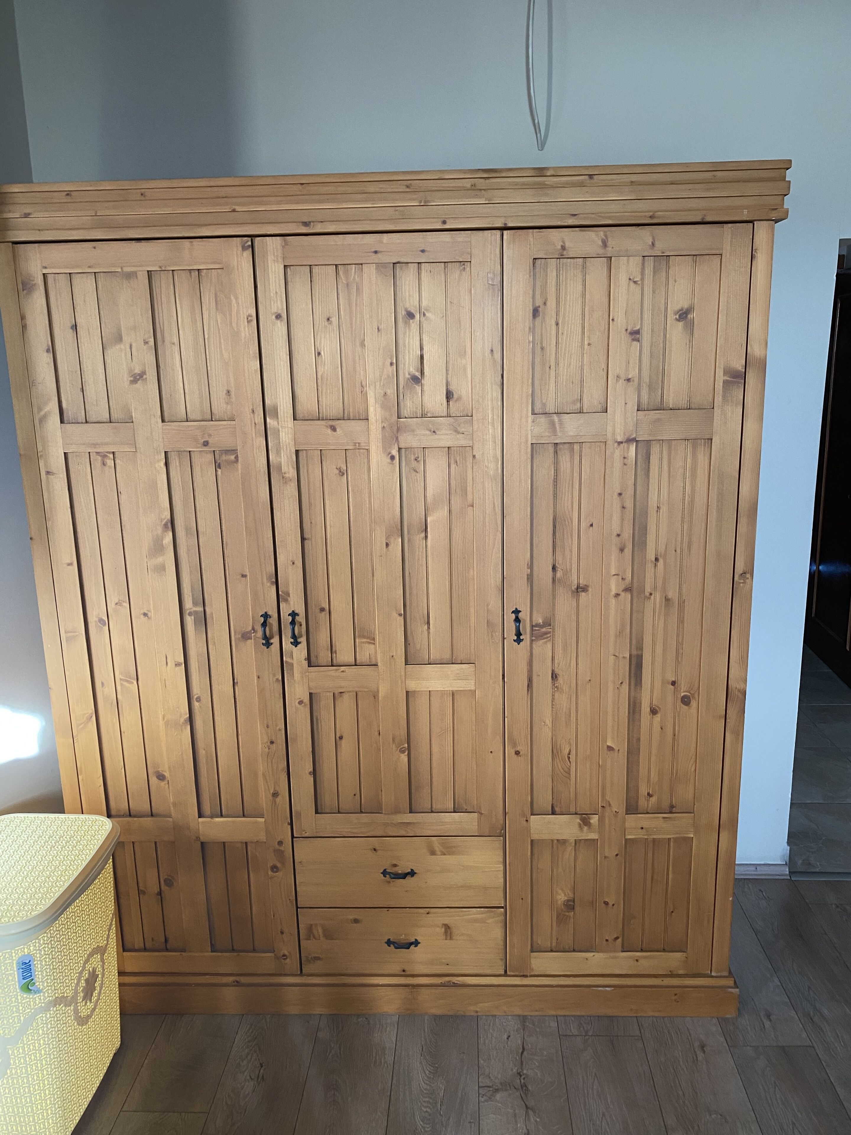 Une armoire en bois à deux portes et deux tiroirs, dotée d’un design simple et de poignées en métal.