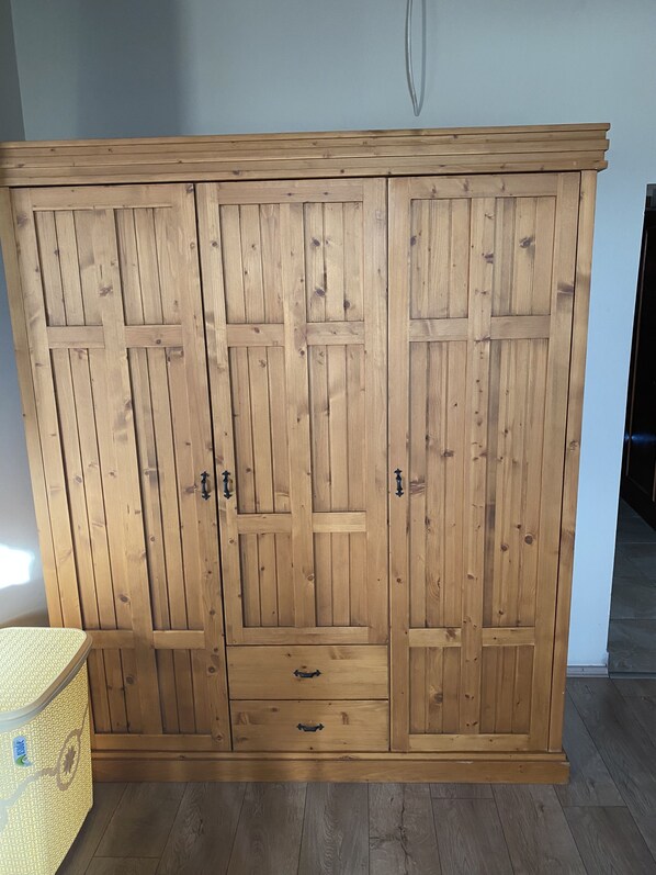 Un armario de madera con dos puertas y dos cajones, de diseño sencillo y tiradores metálicos.
