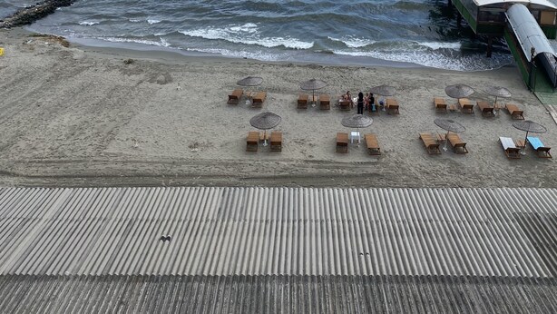 A beach with wooden lounge chairs and umbrellas, a wooden deck, and a pier extending into the water. - ODRYS BEACH HOTEL & RESORT (Tekirdag)