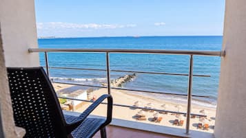Un balcón con vista al mar, una silla y una mesa.