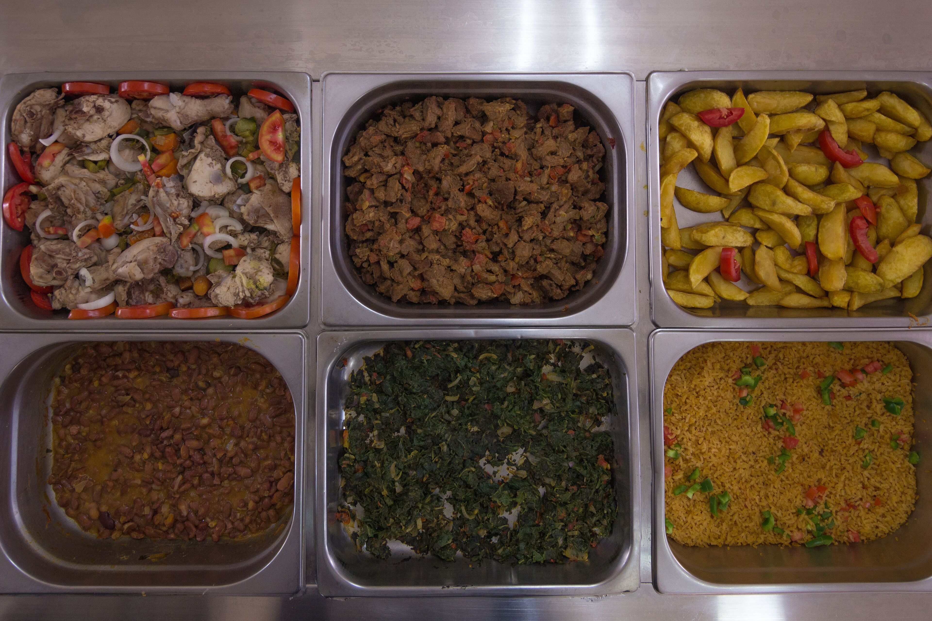 Een buffet met diverse gerechten, waaronder vlees, groenten en rijst.