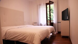 A bedroom with a double bed, a television on a cabinet, and a window with curtains. - Txikierdi Alde (Oiartzun)