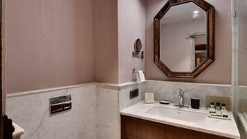 Une salle de bain avec des toilettes blanches, un meuble-lavabo en bois doté d’un miroir et un sol à motifs noir et blanc.