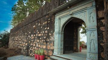 Un muro de piedra con un arco decorativo que lleva a una puerta.