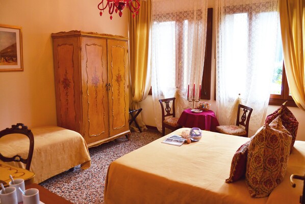 A hotel room with two beds, a wooden wardrobe, a small table with a red tablecloth, and a window with curtains. - Venice Lion Residence - Vespucci (Mestre)