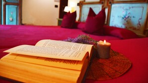 A bed with a red bedspread, a lit candle, and an open book. - Venice Lion Residence - Vespucci (Mestre)