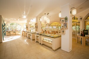 A spacious, well-lit buffet area with multiple serving stations, a coffee bar, and a variety of plants and decorations.