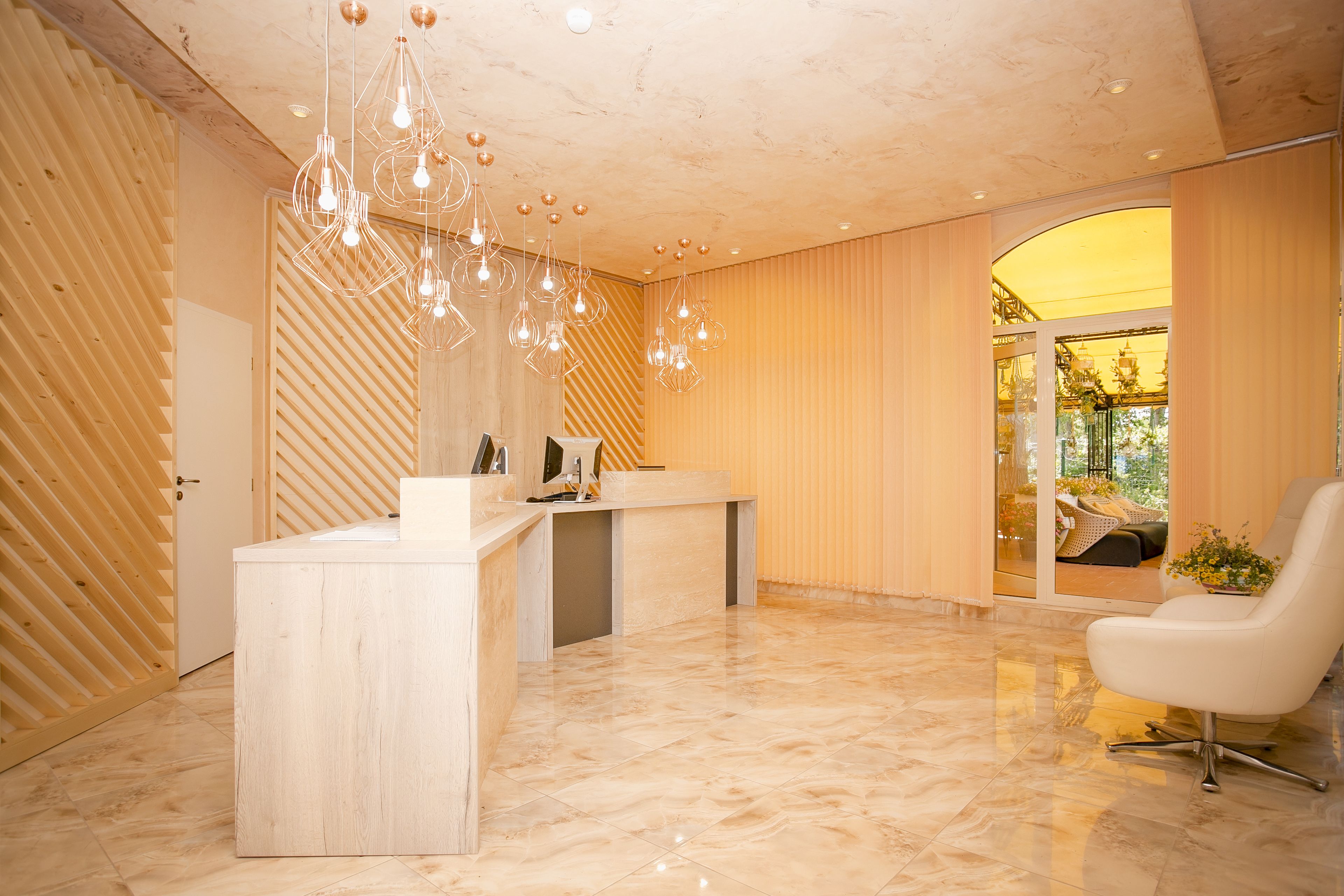 Una zona de recepción moderna con un mostrador de madera, una silla blanca y una puerta de cristal que da a un balcón con vistas al exterior.