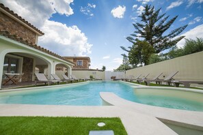 A swimming pool with lounge chairs and a stone building with a tiled roof. - Suimi's Hotel (Villasimius)