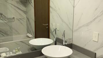 Un baño moderno con dos lavamanos, un espejo grande y paredes de mármol.