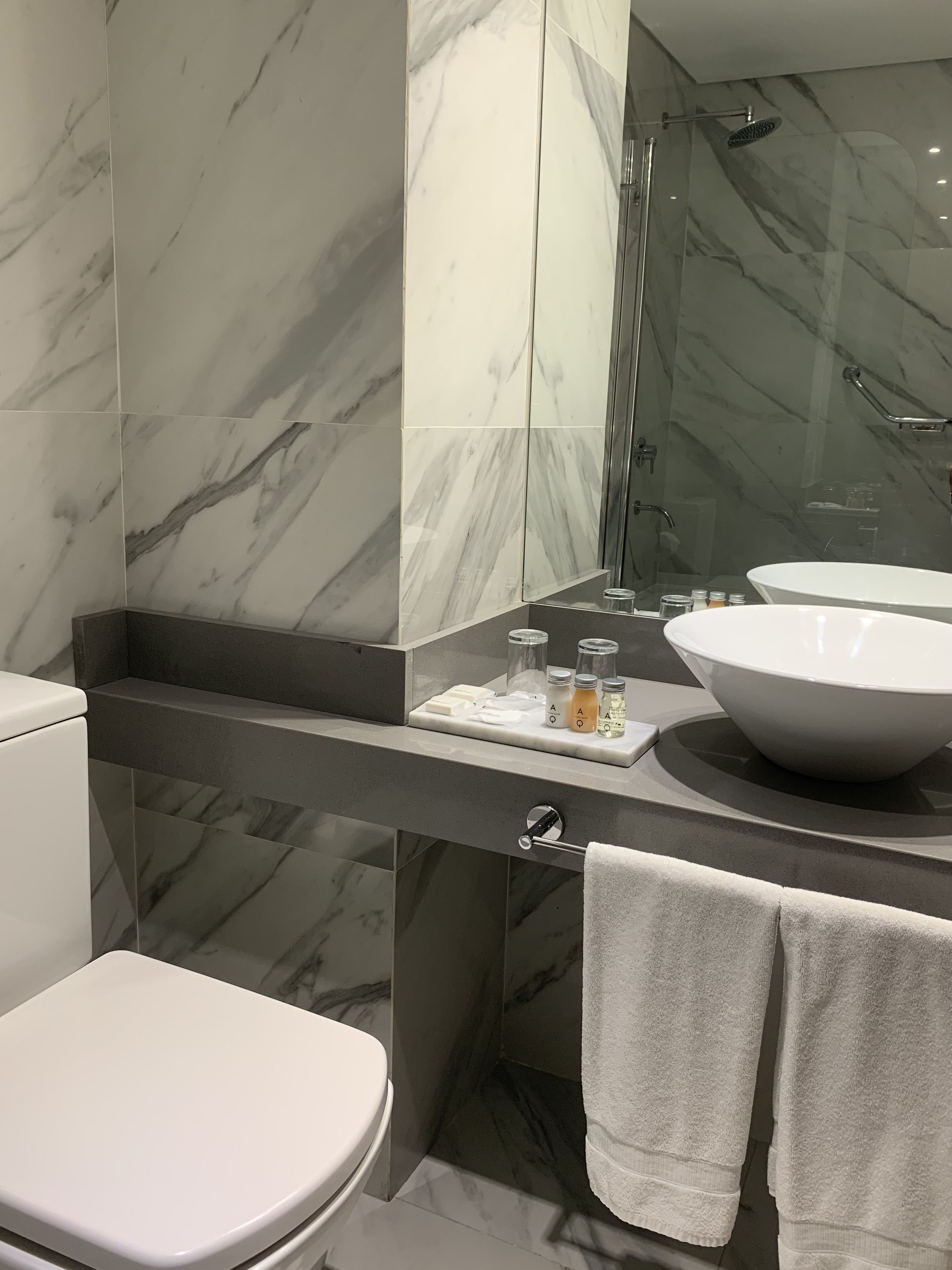 Un baño moderno con un espejo grande, dos lavamanos, un inodoro y una ducha.