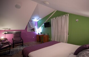A bedroom with a bed, a desk, a chair, and a TV.