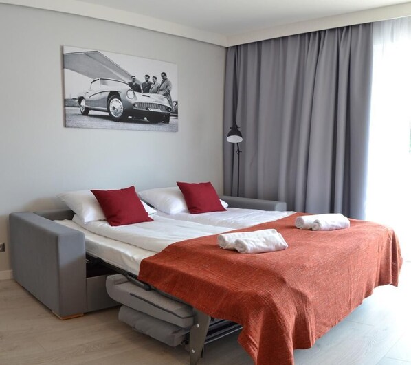 Una habitación de hotel moderna con una cama, un sofá, un escritorio y una lámpara.
