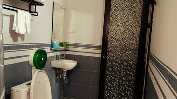 A bathroom with a toilet, sink, towel rack, and a door with a mosaic pattern.