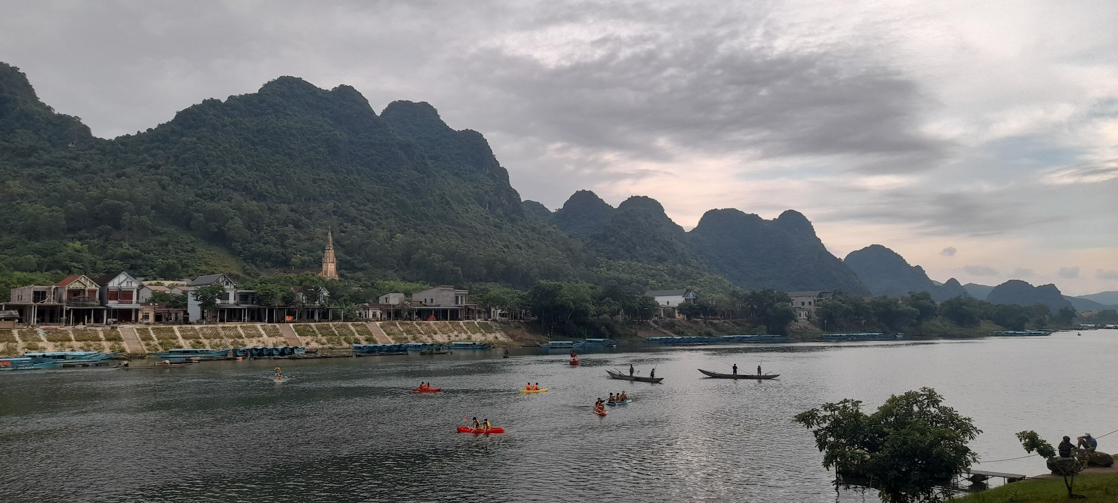 A river with boats, a church, and mountains in the background.