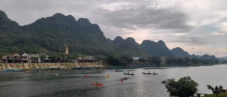 Un río con barcos, una iglesia y montañas al fondo.