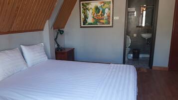 Quarto com uma cama grande, uma mesa de cabeceira, uma luminária de mesa e um quadro na parede.