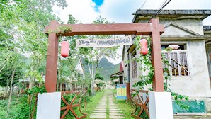 A pathway leading to a bungalow with a sign reading "Phong Sinh Carambola Bungalow".