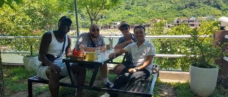 Three people seated at an outdoor table with a view of a lake and houses in the background.