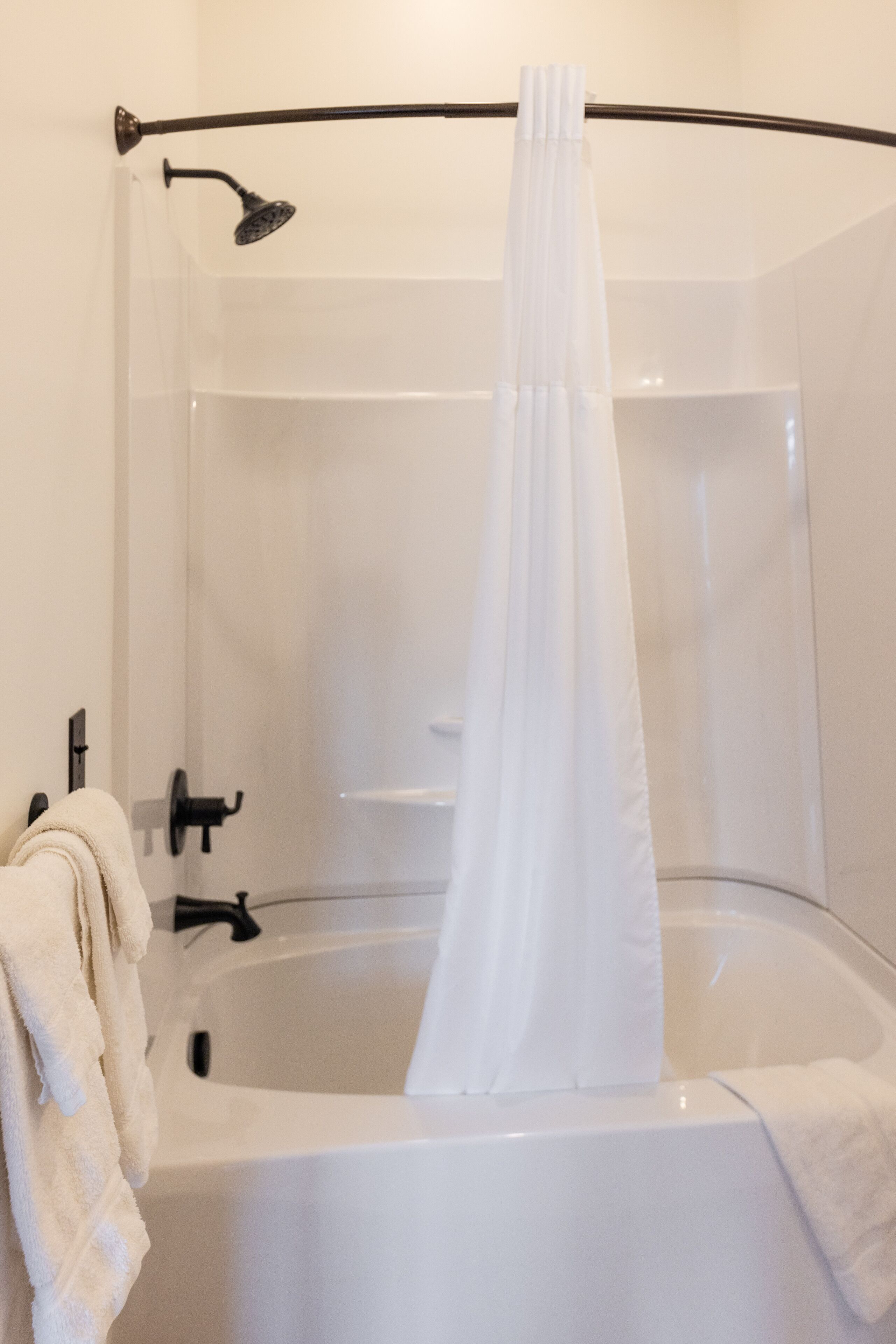 A modern bathroom with a bathtub, a showerhead, and a curtain.