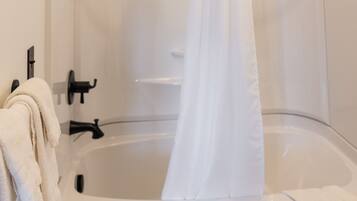 A modern bathroom with a bathtub, a showerhead, and a curtain.