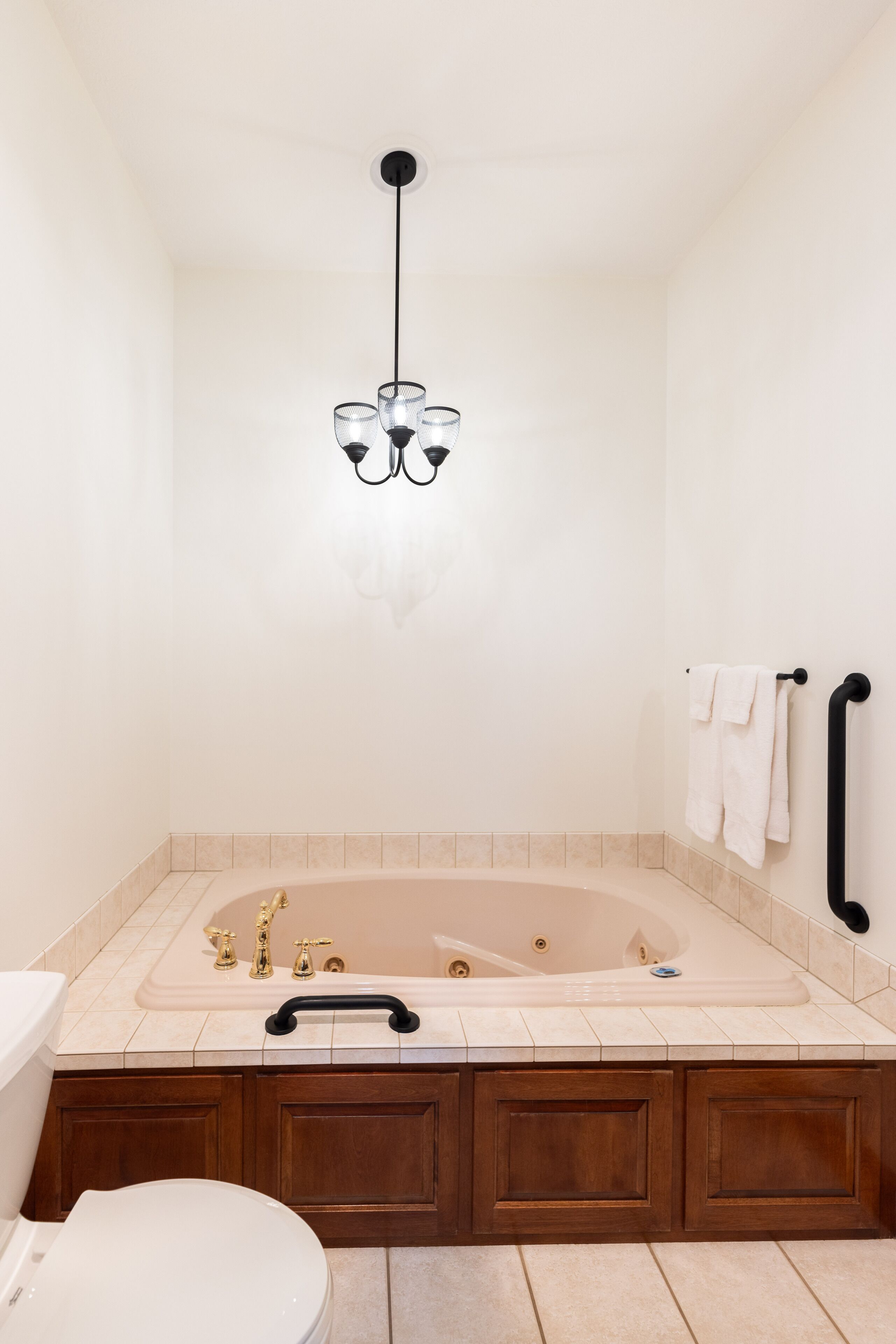 Een moderne badkamer met een vrijstaand bad, toilet en een wastafelmeubel met kastjes.