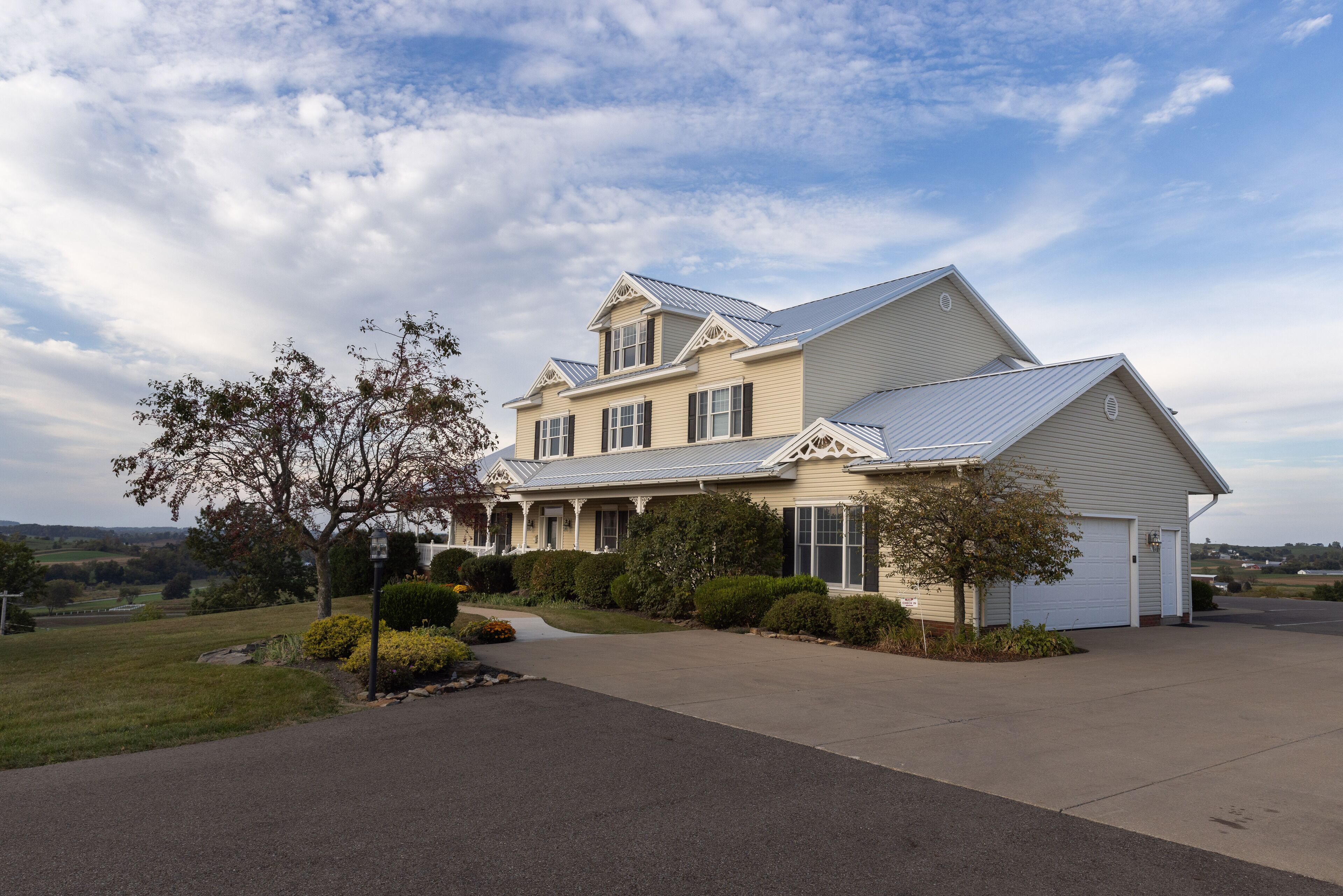 A two-story house with a garage, surrounded by a well-maintained lawn and mature trees.