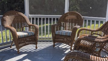 A covered porch with wicker furniture and a wooden floor.