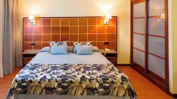A hotel room with a large bed, two bedside lamps, a wooden headboard, and a sliding door.