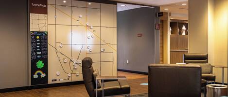 A hotel lobby with a seating area, a map display, and a reception desk.