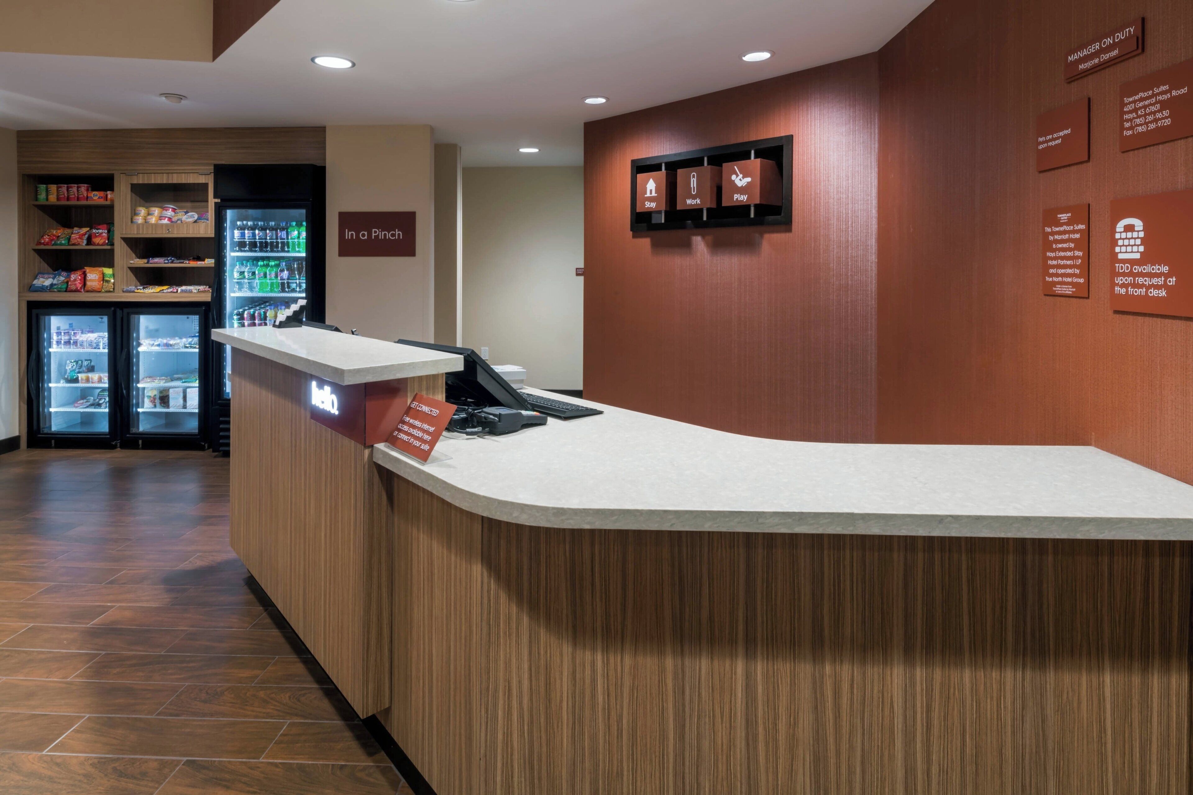 A reception area with a counter, a refrigerator stocked with beverages, and a wall with informational signs.