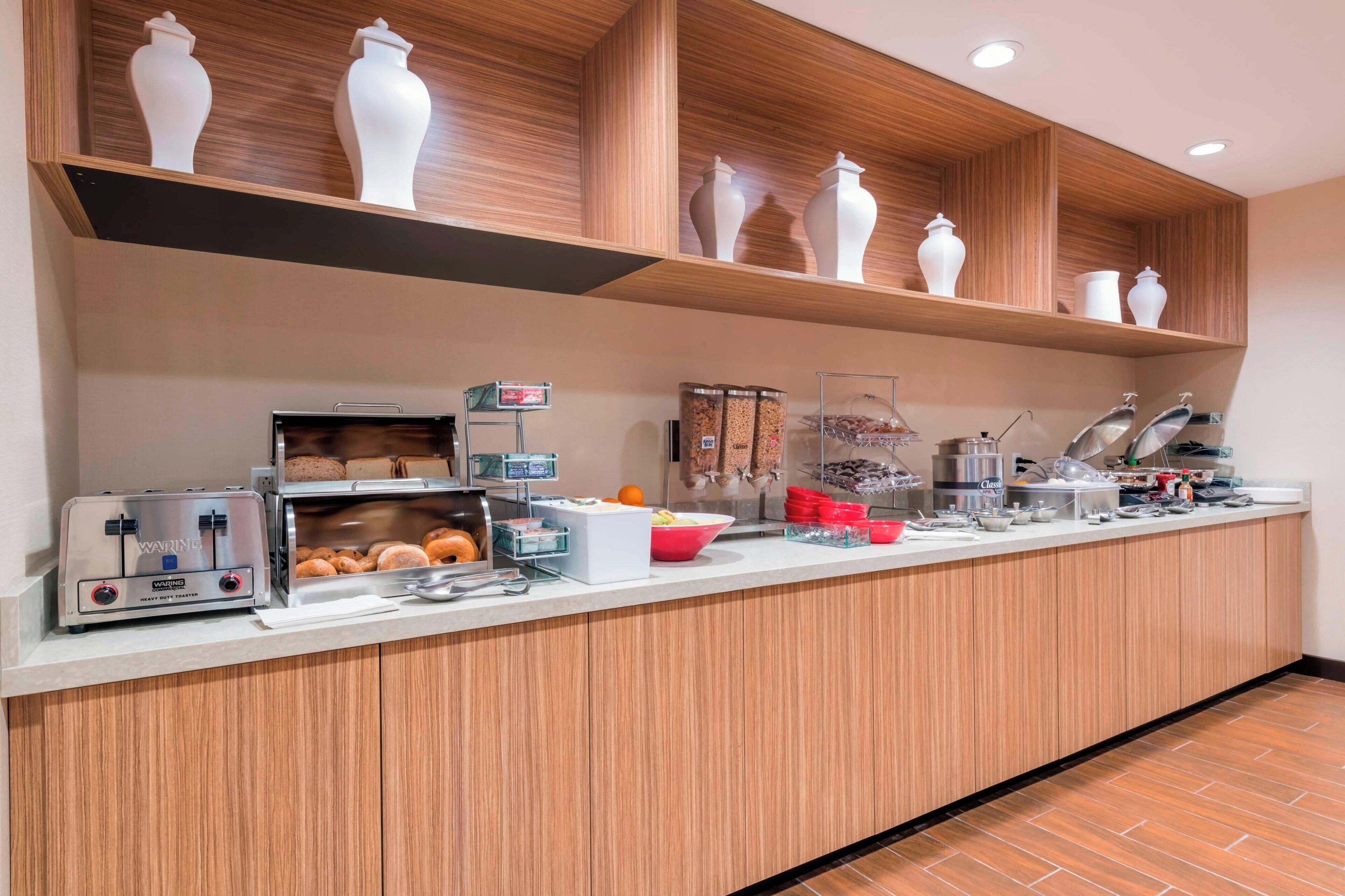 A breakfast bar with a toaster, a coffee machine, and various food items.