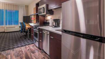 Una cocina de hotel compacta con microondas, cafetera y lavavajillas.