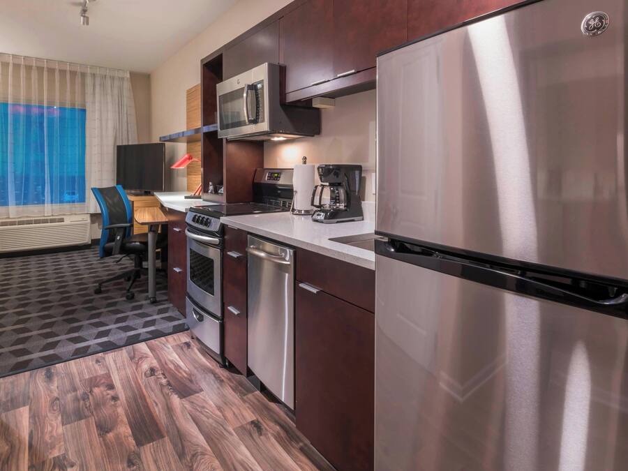 Una cocina de hotel compacta con microondas, cafetera y lavavajillas.