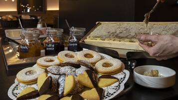 Una varietà di dolci e dessert su un tavolo, tra cui biscotti a forma di cuore e un vassoio di ciambelle.