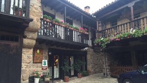 A rustic building with a stone facade, wooden balconies with potted plants, and a sign indicating rural lodging. - Posada Reserva Verde (Los Tojos)