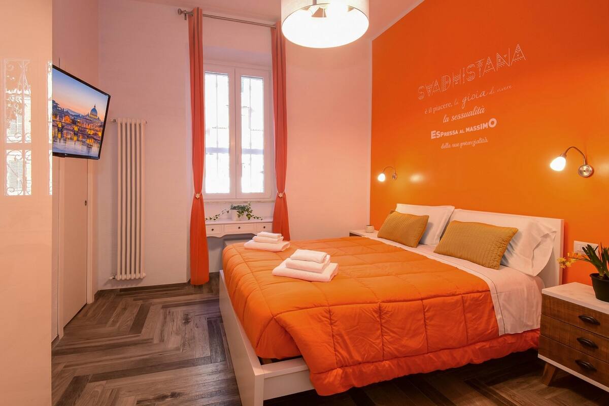 A bedroom with a bed, a window, a radiator, a TV, and a wall with text.