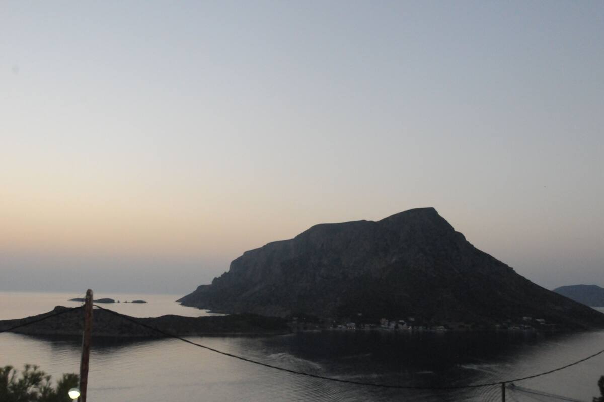 A mountainous landscape with a body of water in the foreground and a small settlement at the base of the mountain.
