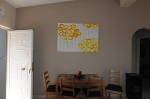 A dining area with a table, chairs, and a wall art piece.