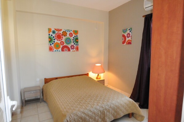 A bedroom with a bed, a nightstand, a lamp, and two wall art pieces.